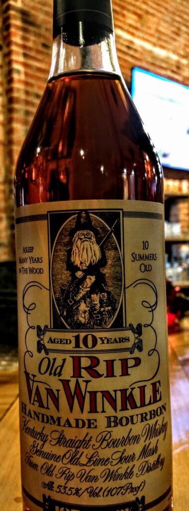 A bottle of old rip van winkle is sitting on a wooden table.