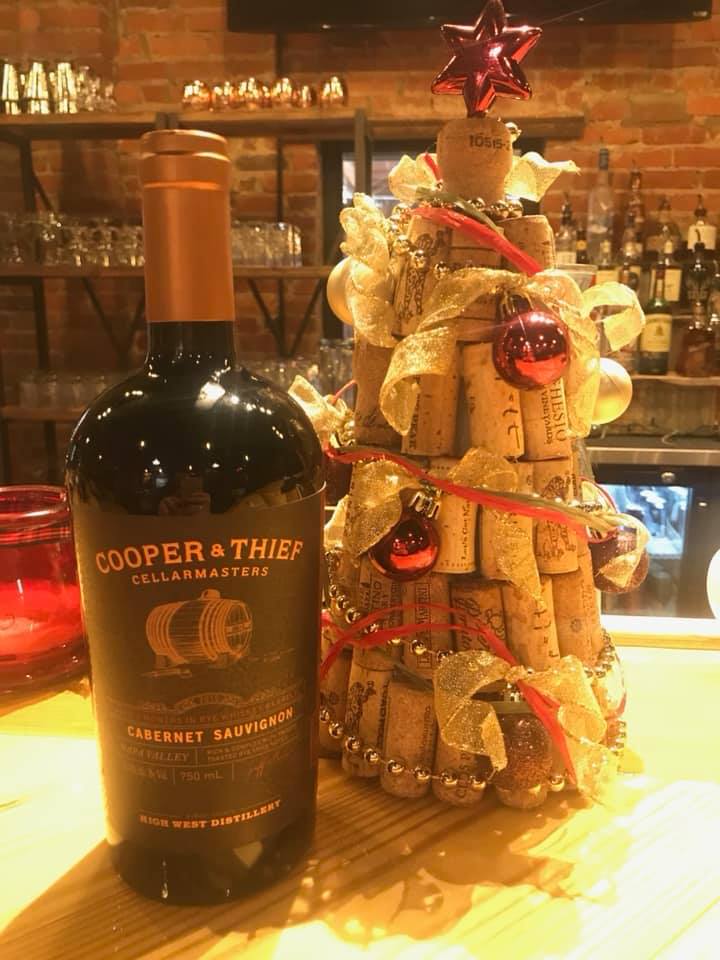 A bottle of wine next to a christmas tree made out of corks