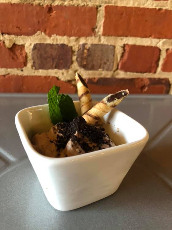 A small white bowl filled with ice cream and mint leaves