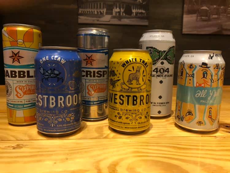 A group of cans of beer are sitting on a wooden table.