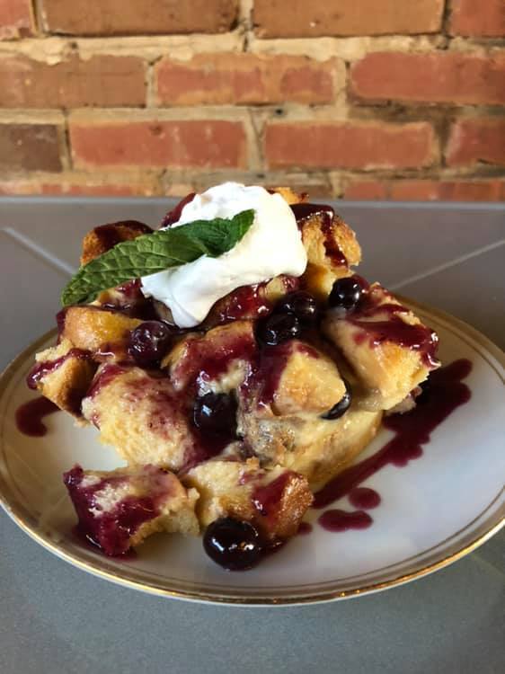 A white plate topped with a piece of bread pudding and whipped cream.