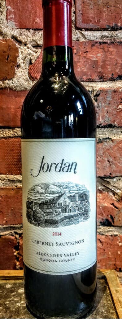 A bottle of red wine is sitting in front of a brick wall.