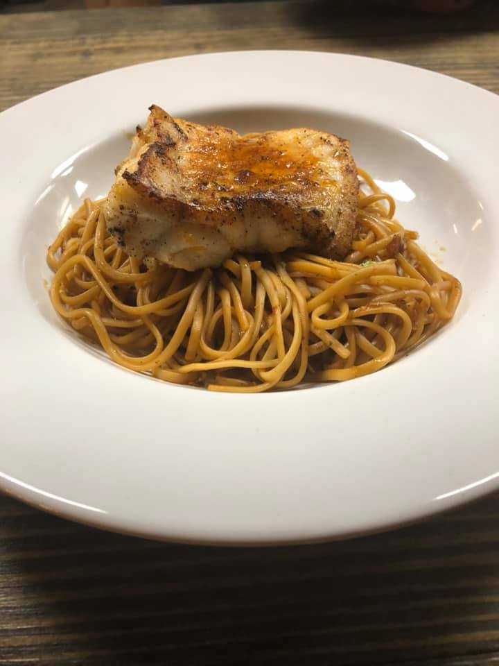 A white plate topped with spaghetti and a piece of meat.