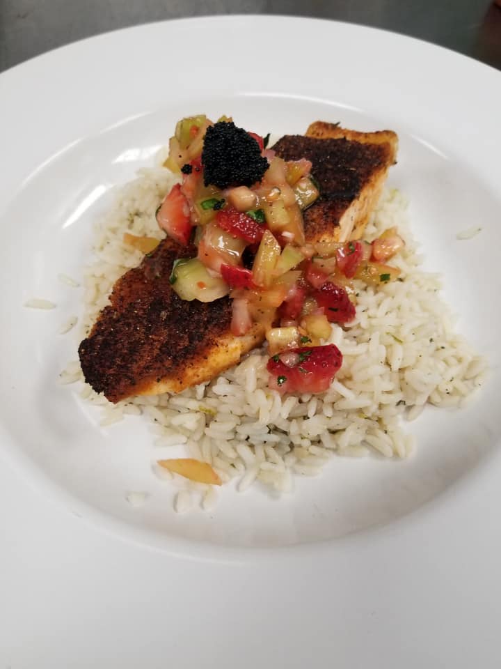 A white plate topped with rice and a piece of fish.
