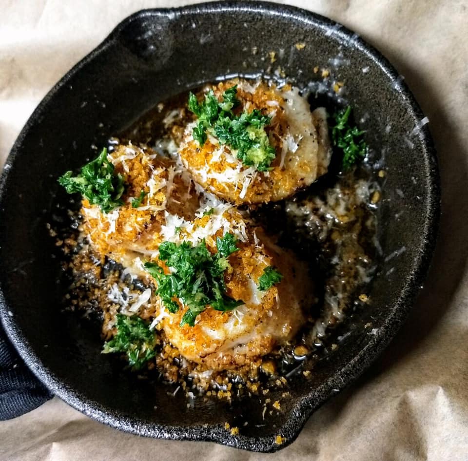 A skillet filled with food with parsley on top