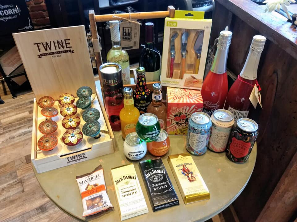 A table topped with bottles , cans , chocolates , and other items.