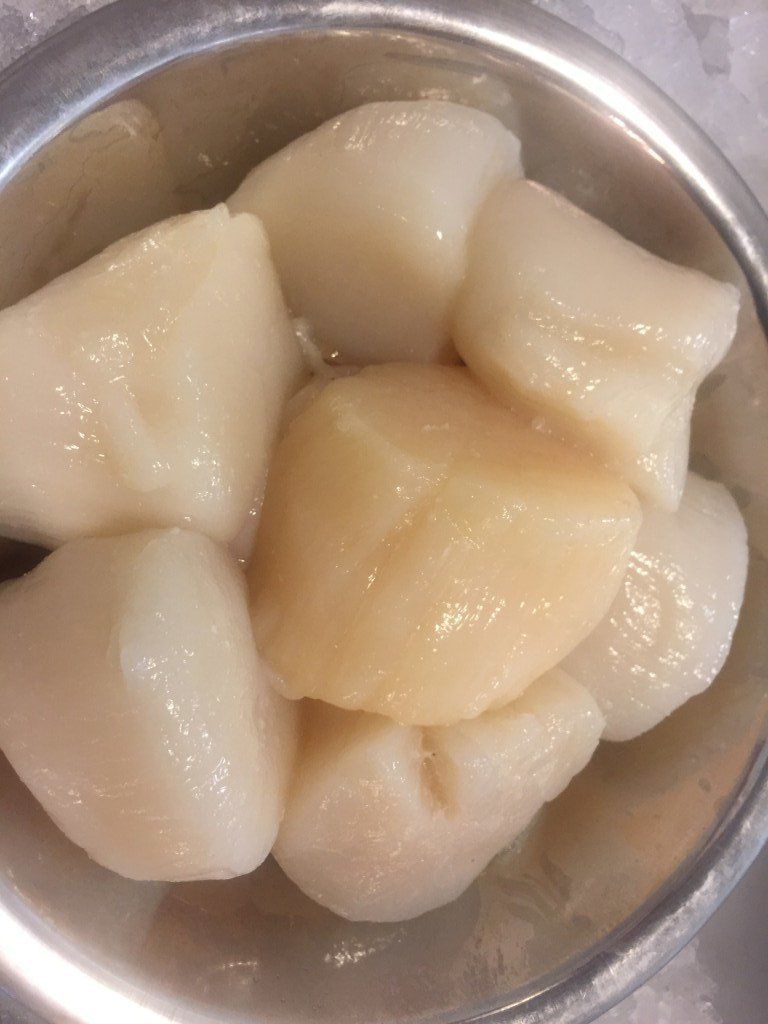 A bowl of scallops is sitting on a table.