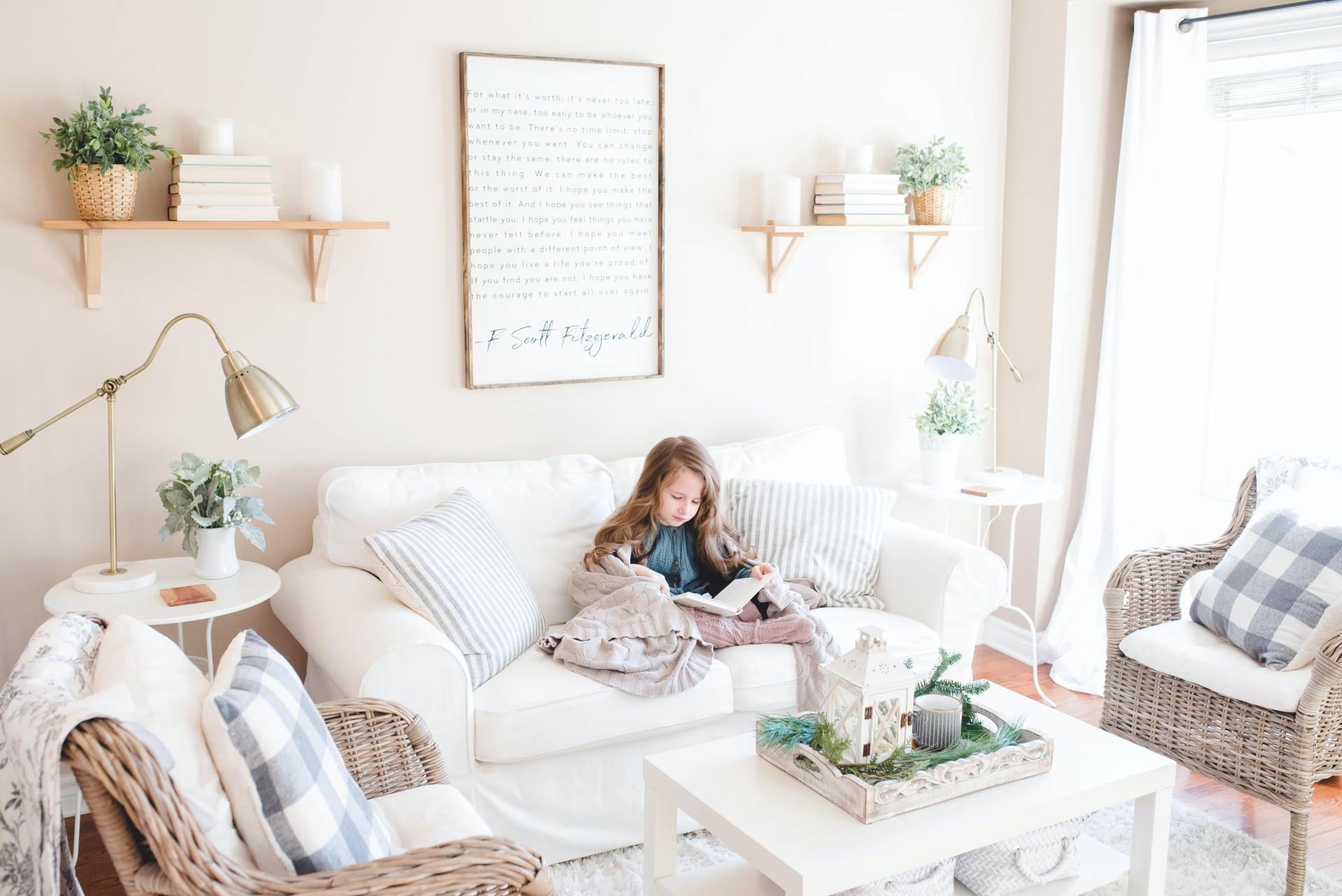 A little girl is sitting on a couch reading a book.