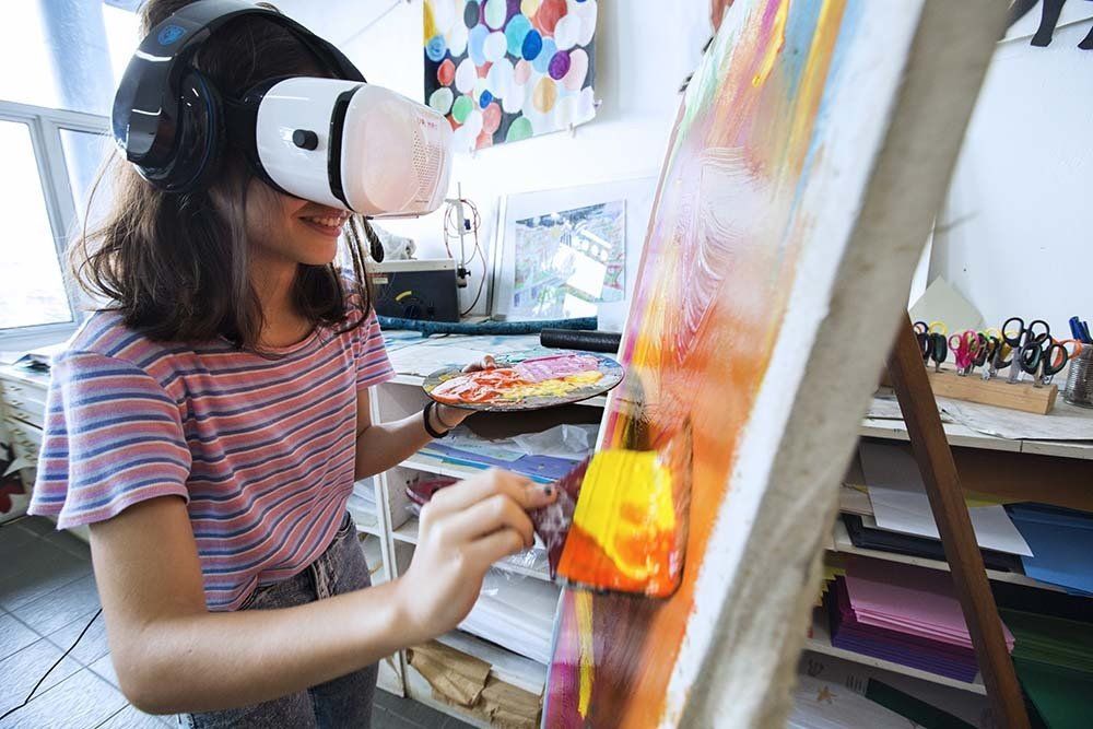 A woman wearing a virtual reality headset is painting a picture.