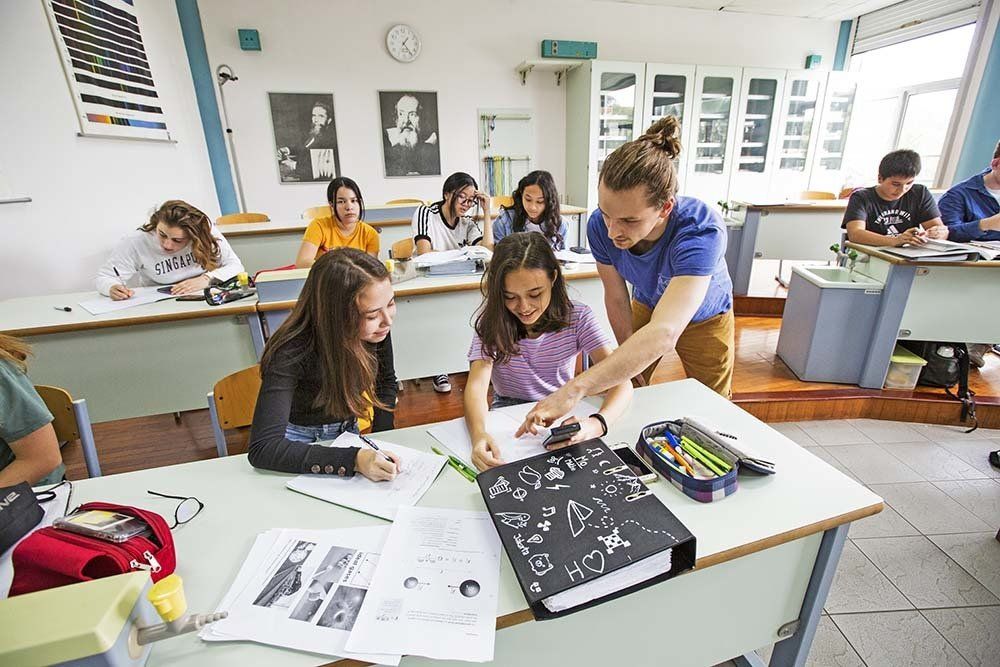 A teacher is helping a girl with her homework in a classroom.