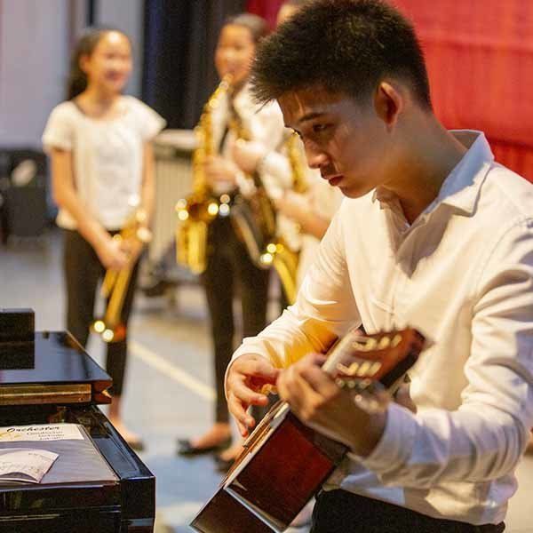 A man in a white shirt is playing a guitar