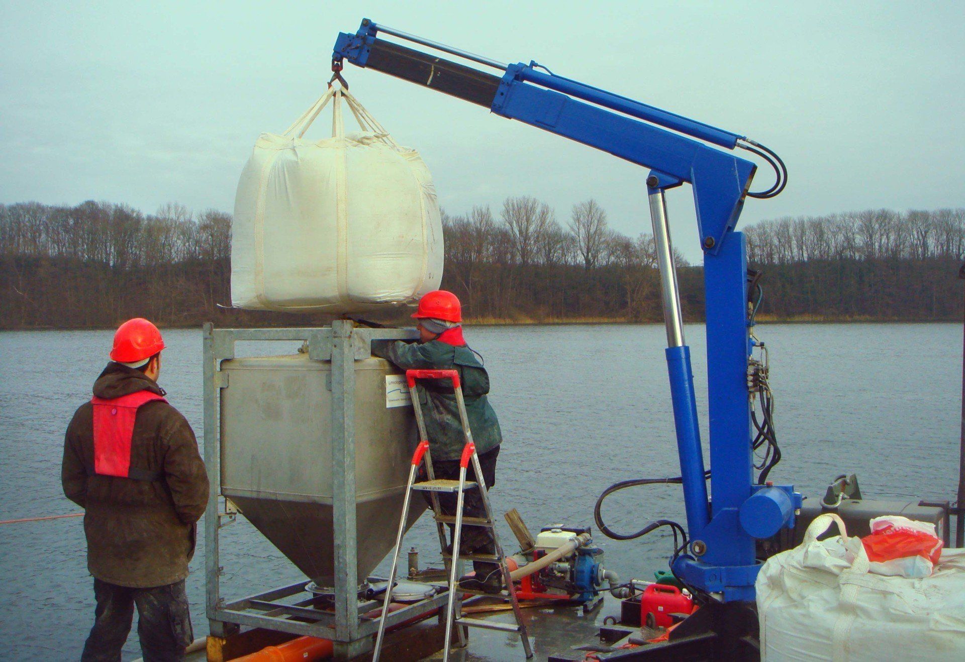 A blue crane is lifting a large white bag