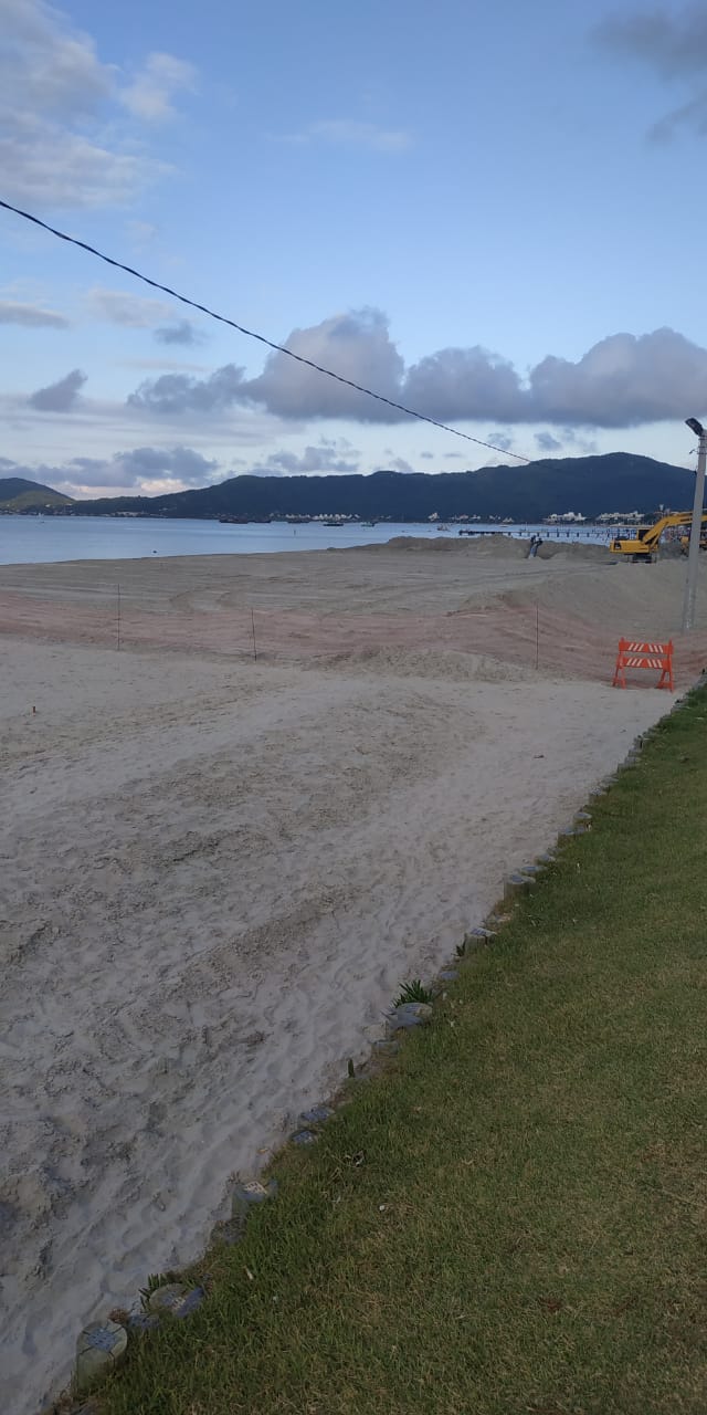 Uma estrada de terra que leva a uma praia com montanhas ao fundo.