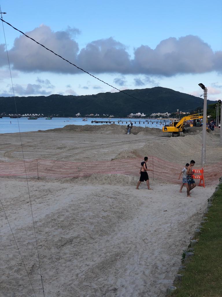 Um grupo de pessoas está jogando vôlei em uma praia arenosa