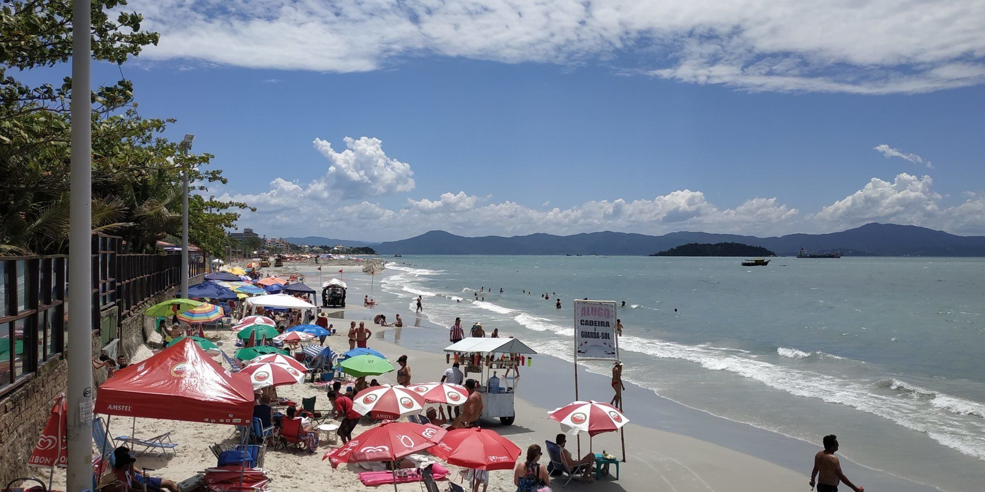Uma praia cheia de gente e guarda-sóis em um dia ensolarado