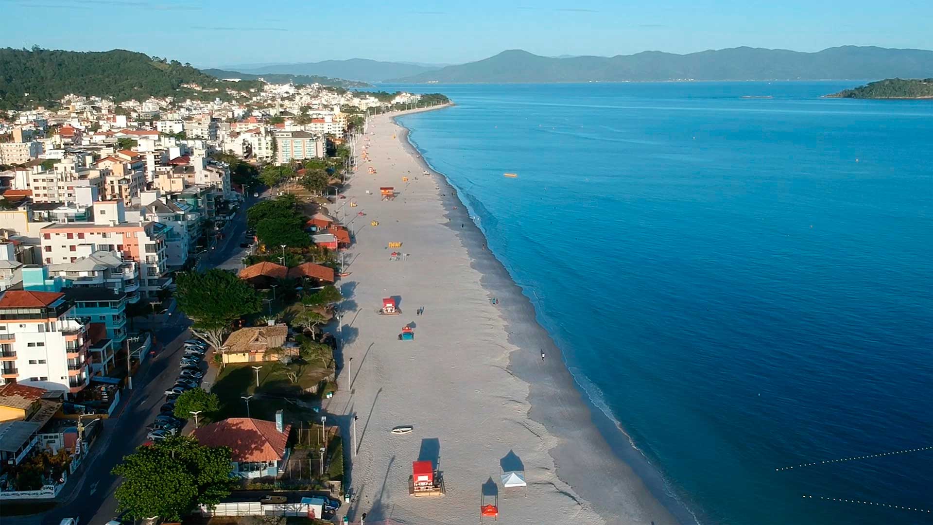 Vista aérea de uma praia com uma cidade ao fundo