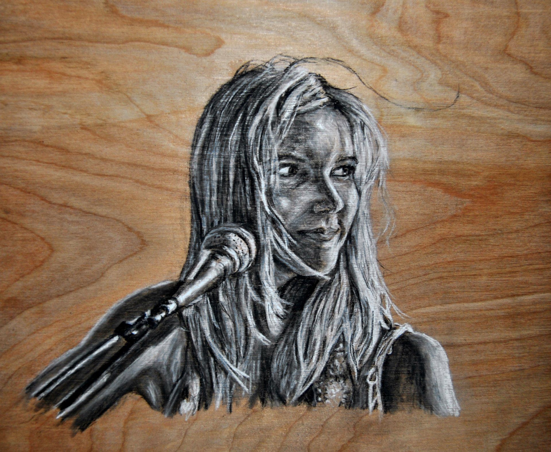 Black and white drawing of a singer with long hair, holding a microphone. Set on a wood background.
