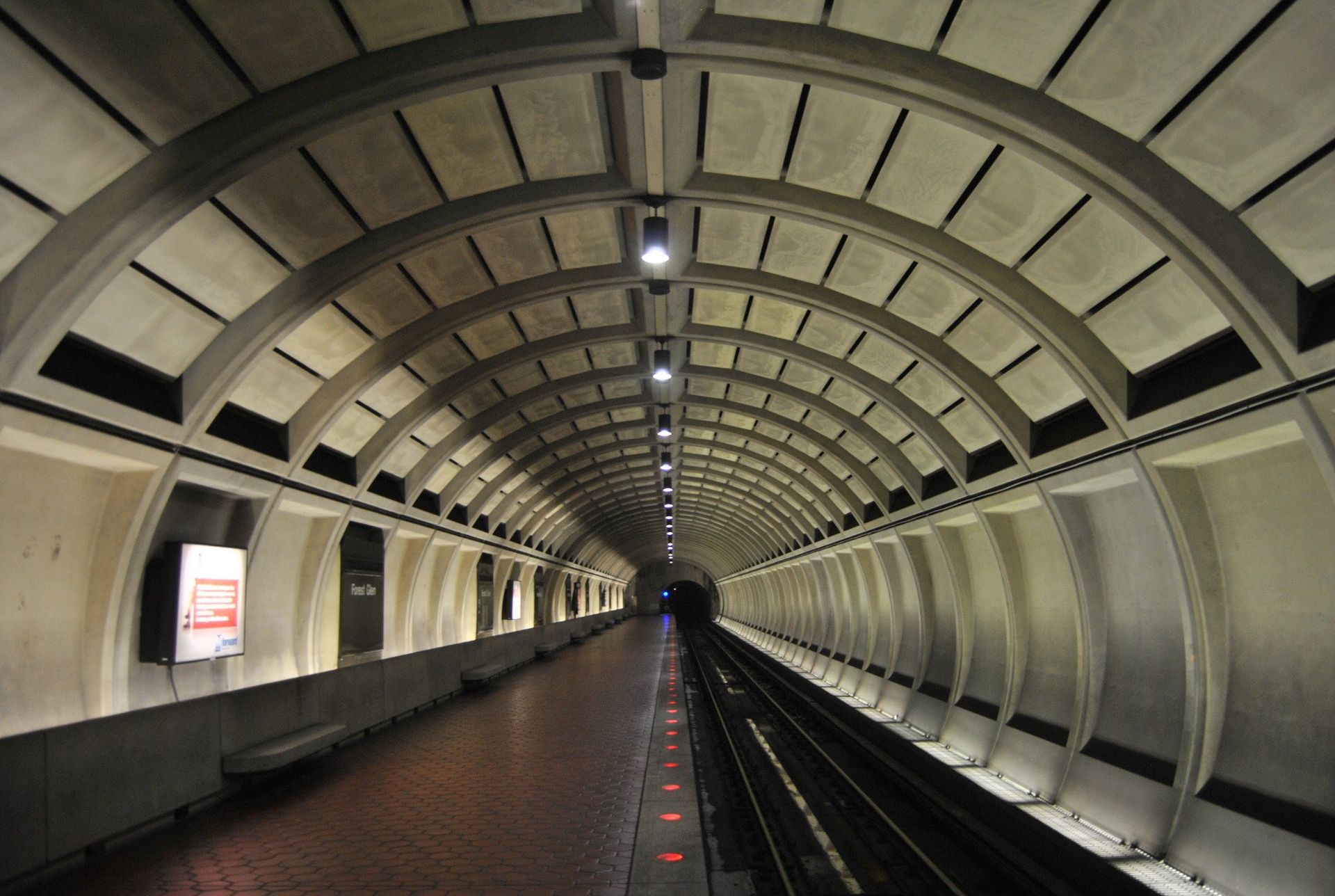 Subway platform with arched ceiling, tracks on the right, and benches on the left.