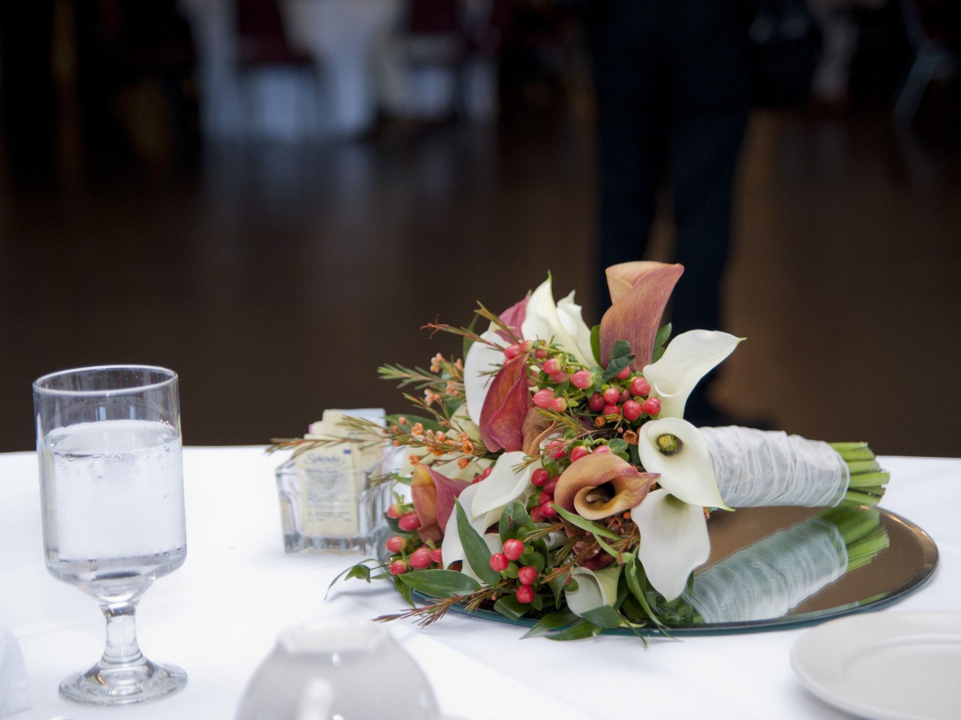 Table setting with floral arrangement, water glass, and mirrored base.