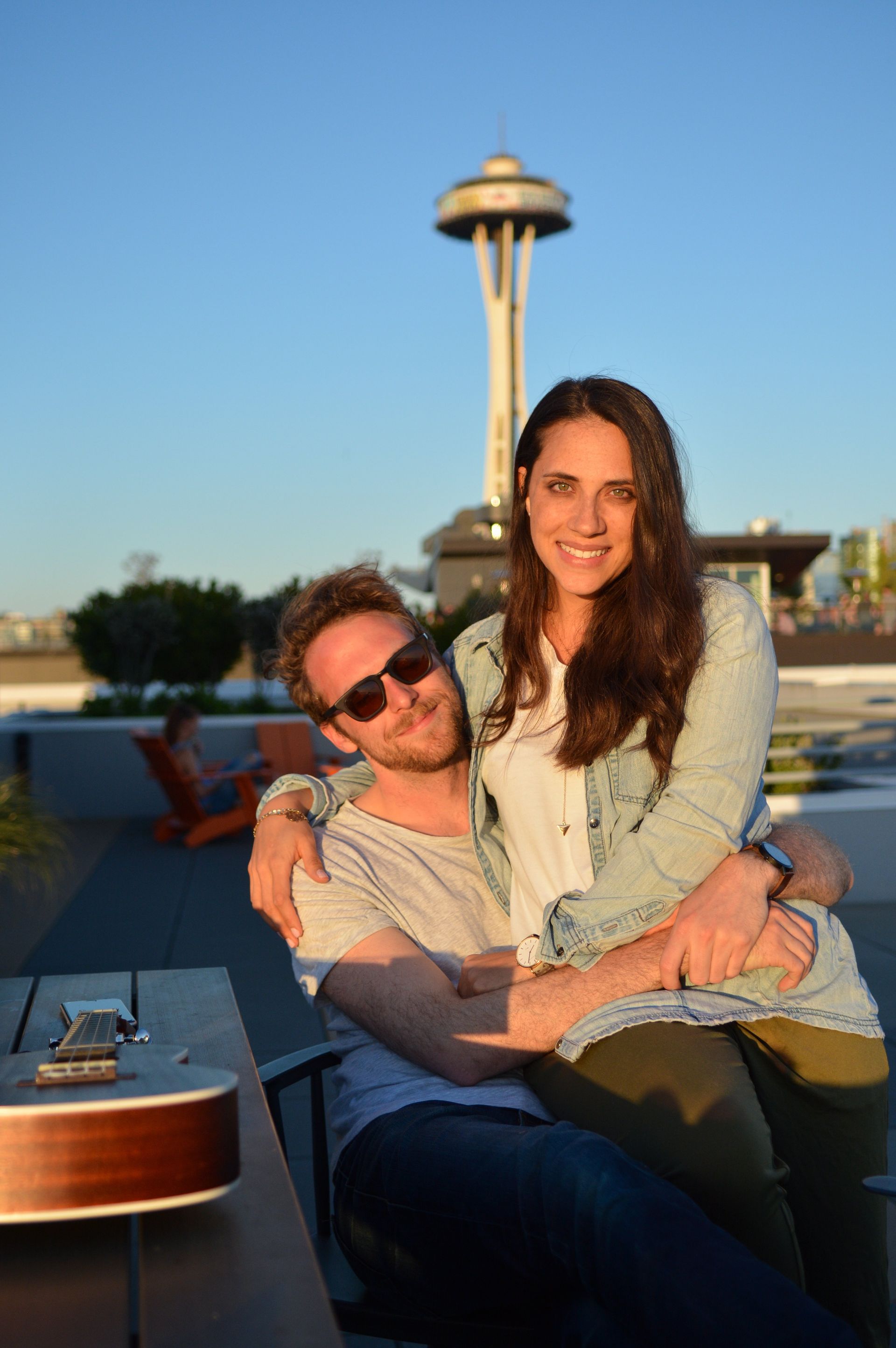 Couple embracing outdoors with Seattle Space Needle in the background.