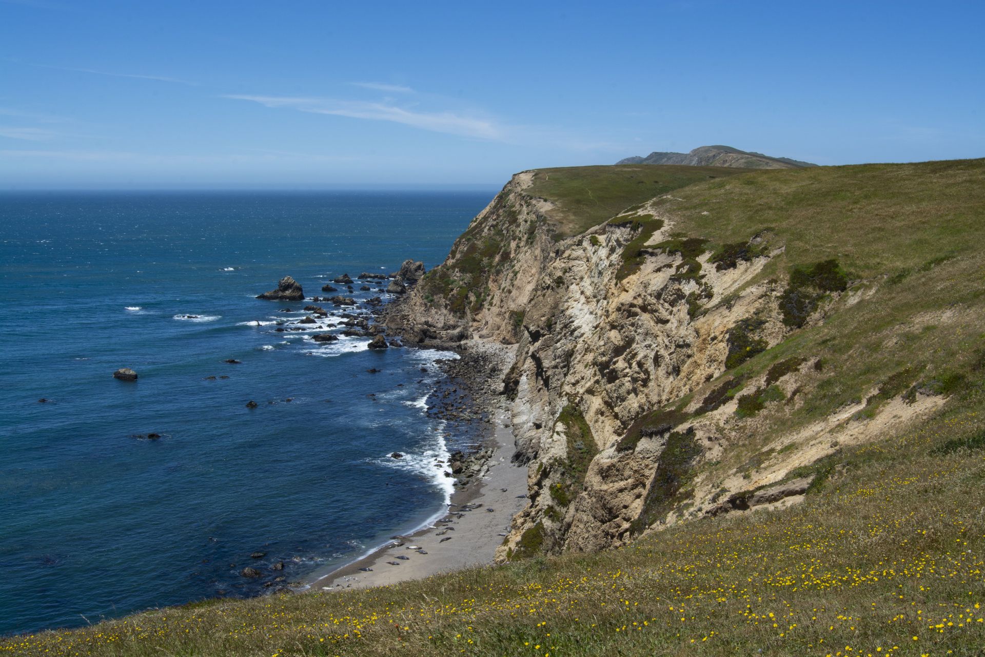 Rocky coastline with cliffs meeting the blue ocean under a bright sky.