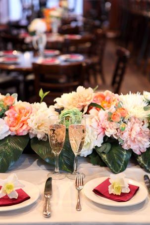 A table with plates , utensils , and flowers on it for a wedding reception.
