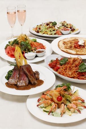 A table topped with food for a wedding party from Shooters and two glasses of champagne.