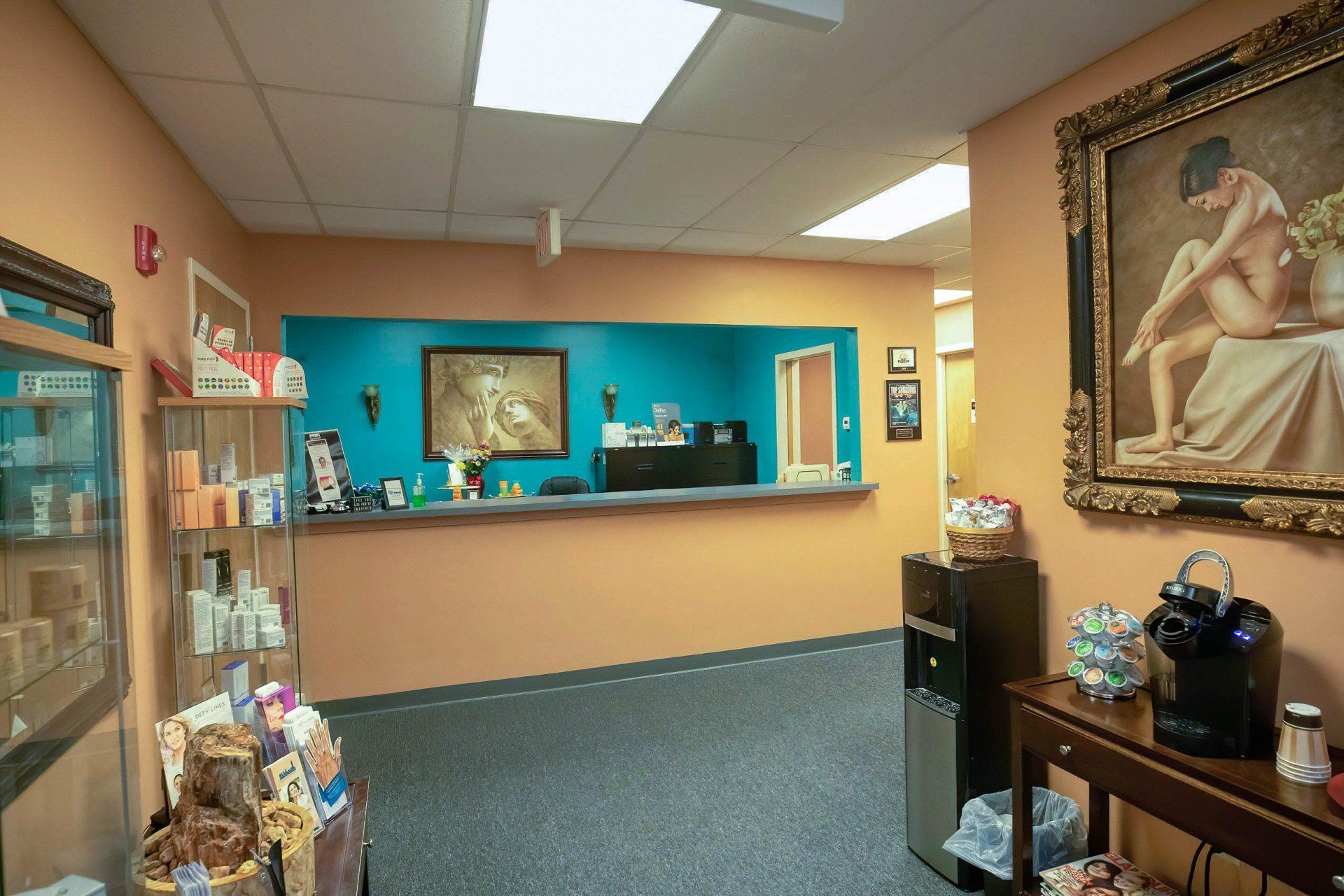Reception area with orange walls, teal accent, front desk, artwork, and product displays.