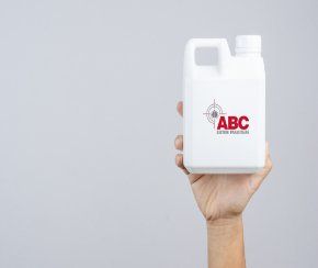 Main tenant un récipient en plastique blanc portant le logo ABC, un motif cible et du texte.
