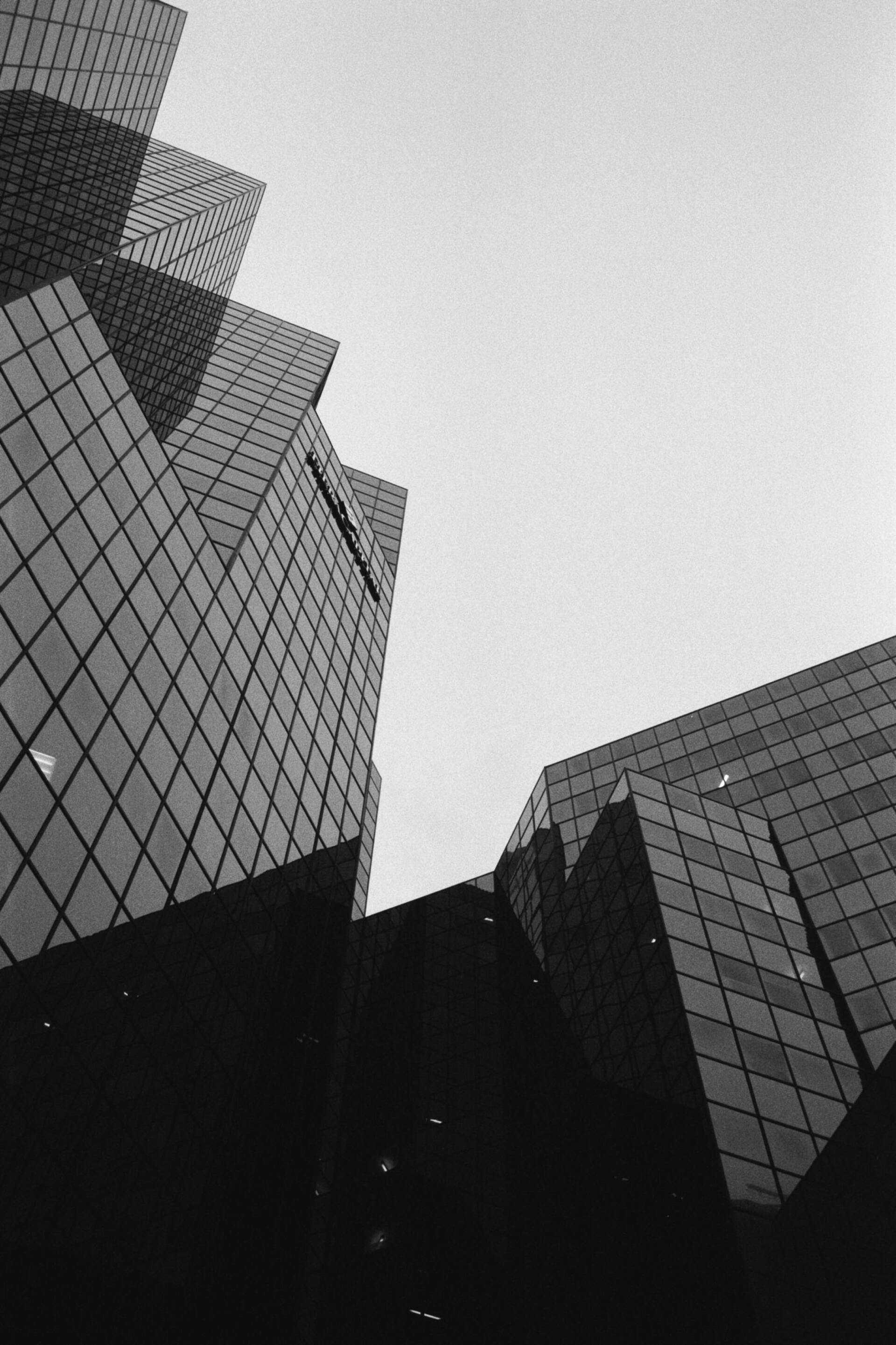 Photo en noir et blanc d'un bâtiment moderne au design géométrique, sur fond de ciel nuageux.