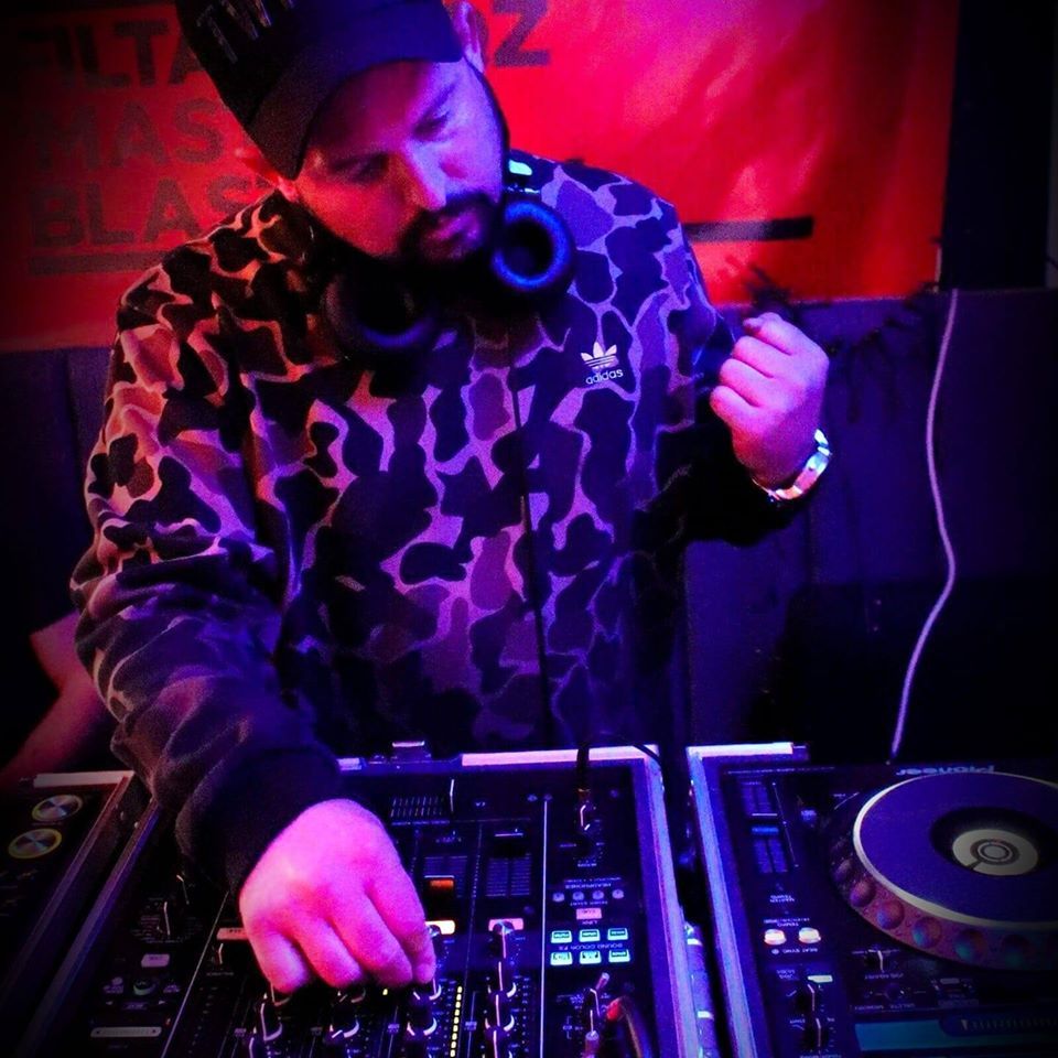 A man wearing headphones and an adidas shirt is playing music