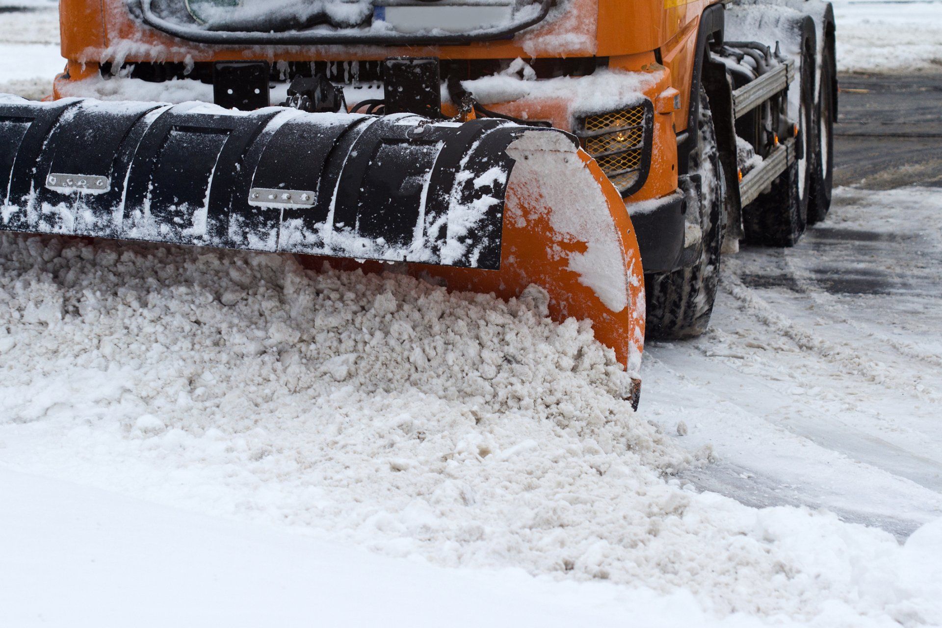 Orange Snow Plug Working on a City Street by Removing Snow — Ballwin, MO — Asi American Snow & Ice