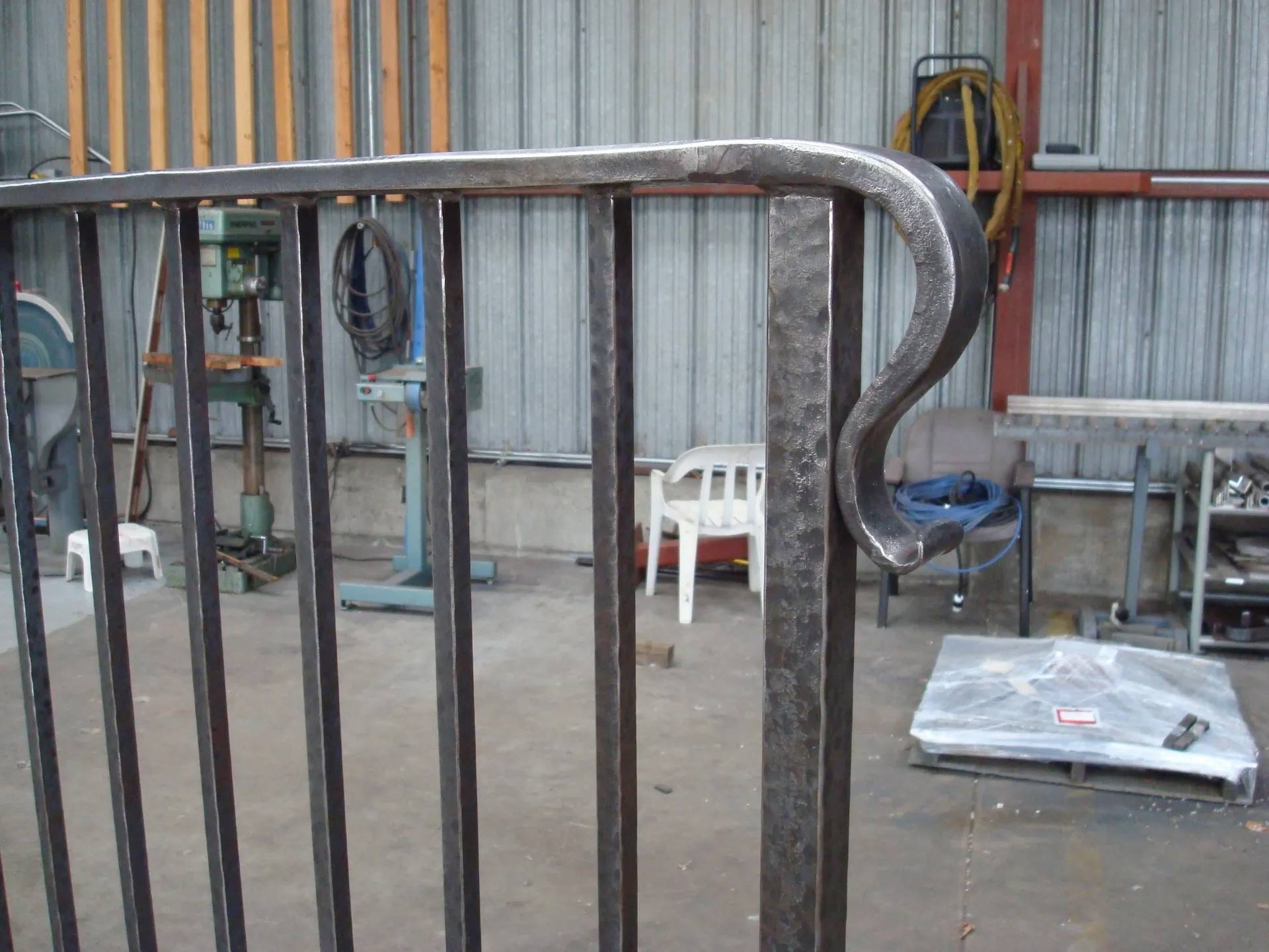 Black iron railing with a curved top section and vertical bars in a workshop setting.