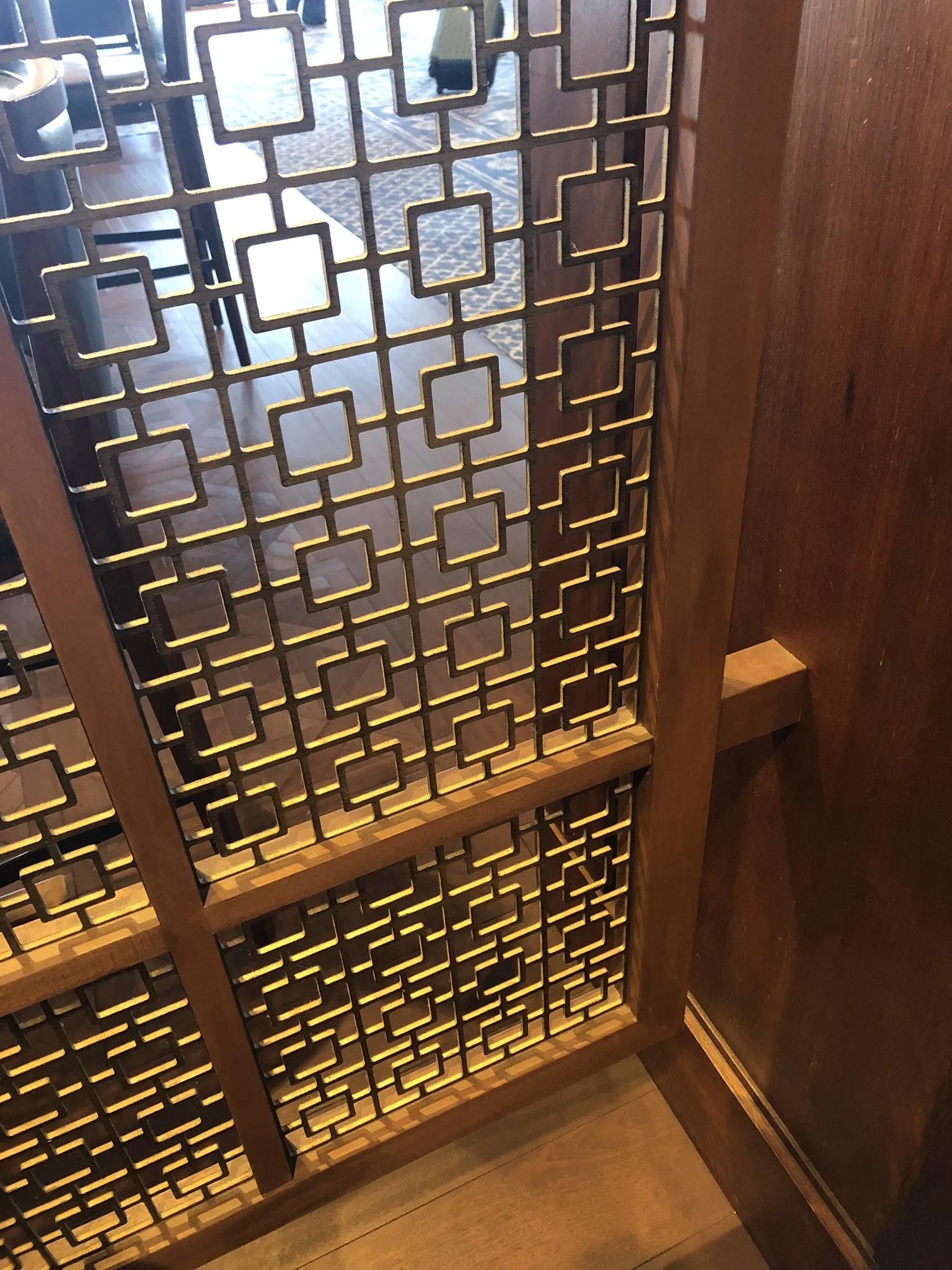 Wooden screen with geometric square pattern in a room with hardwood.