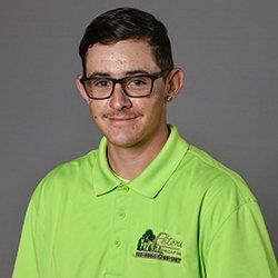 Man with glasses wearing a green polo shirt, smiling at the camera.