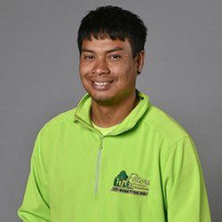Man in a green shirt smiles at the camera; a logo on the chest.