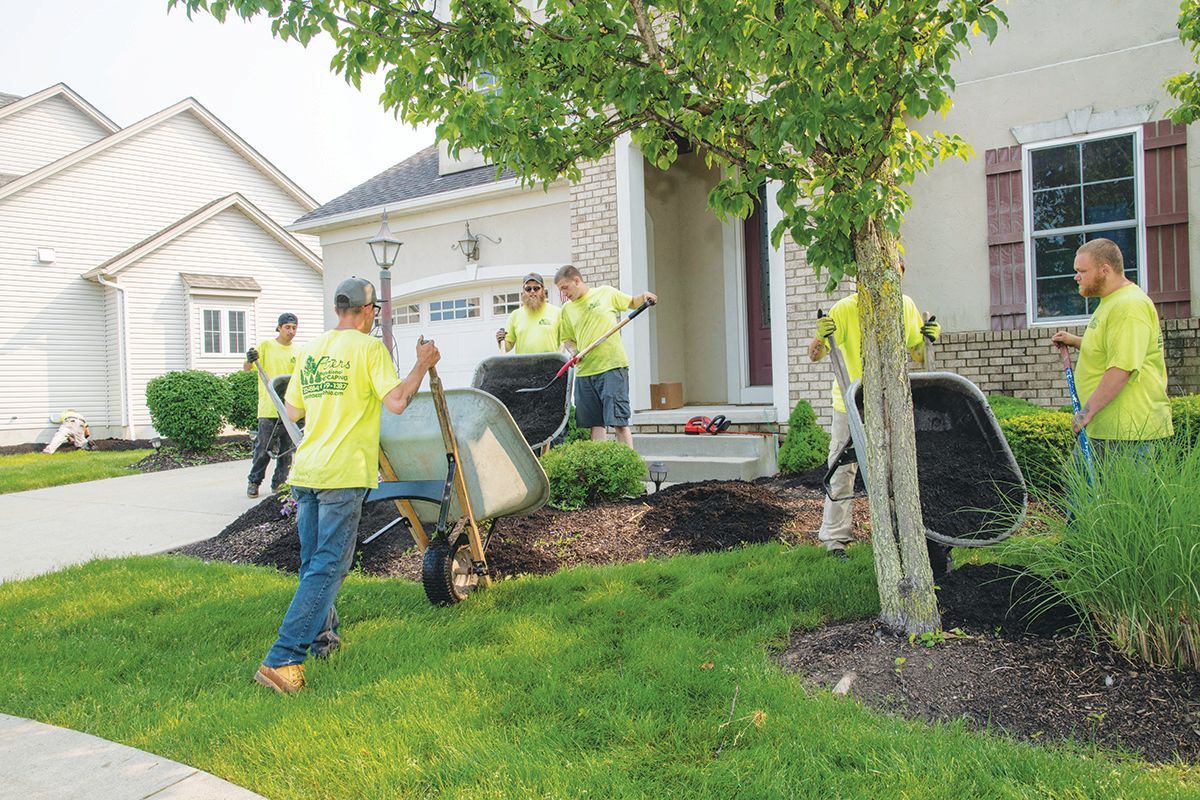 Landscapers in neon yellow shirts working on a yard.