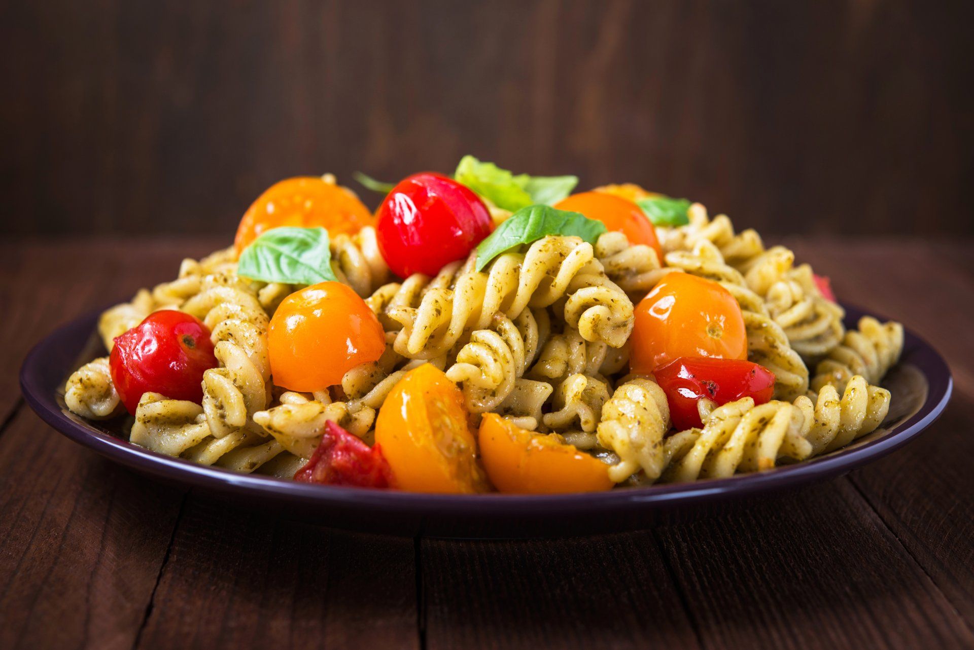 Fusili Pasta Salad with cherry tomatoes in a bowl on wooden table