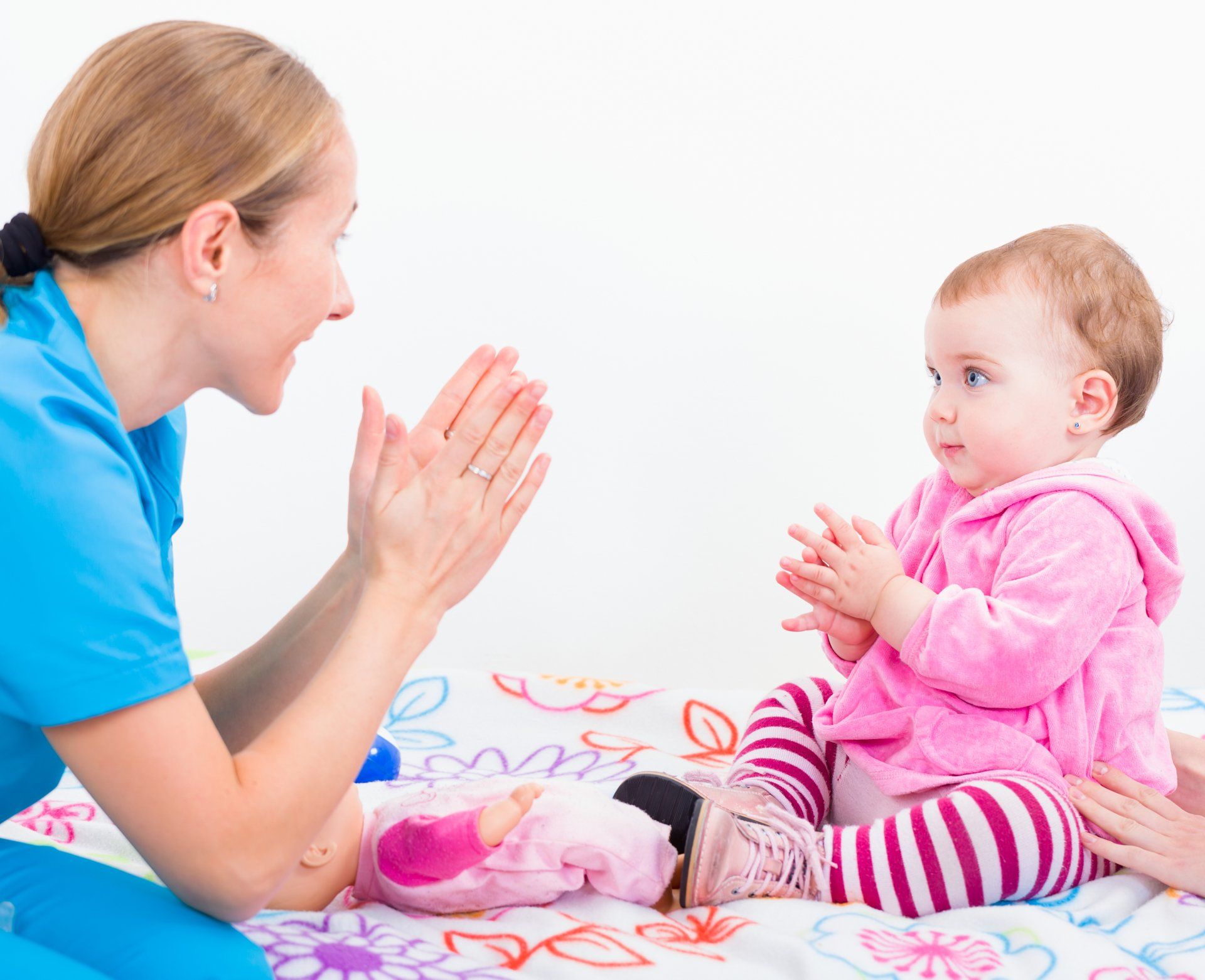 A woman is giving a baby a high five while sitting on a bed.