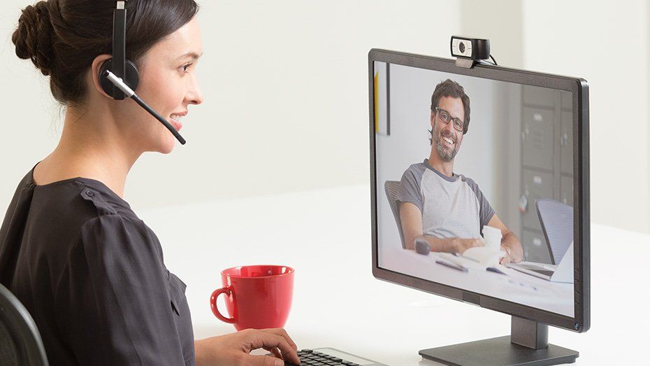 Una donna che indossa un auricolare è seduta davanti al monitor di un computer 
