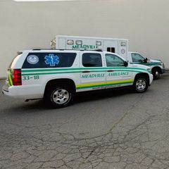 Meadville ambulance SUV parked on pavement, white with green stripes and blue Star of Life emblem
