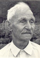 Zwart-wit portret van een oudere man met wit haar en een snor, die opzij kijkt.