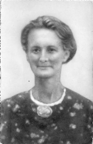 Zwart-wit portret van een vrouw met kort haar, gekleed in een jurk met patroon en een ronde hangerketting.