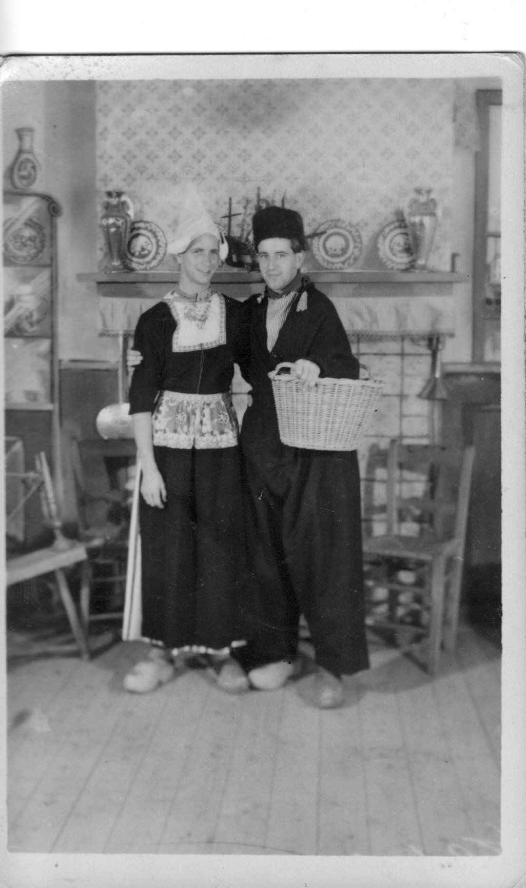 Twee mensen in traditionele kleding staan ​​in een versierde kamer en houden dienbladen met patronen vast.