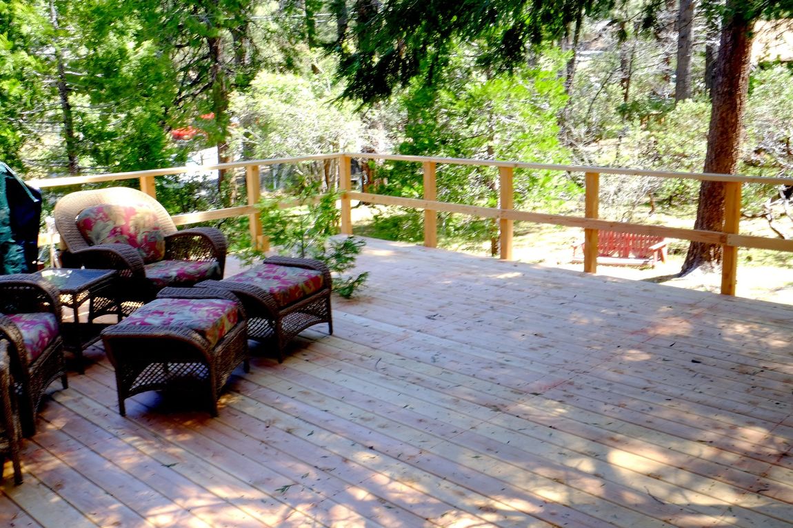 A wooden deck with wicker furniture and a grill