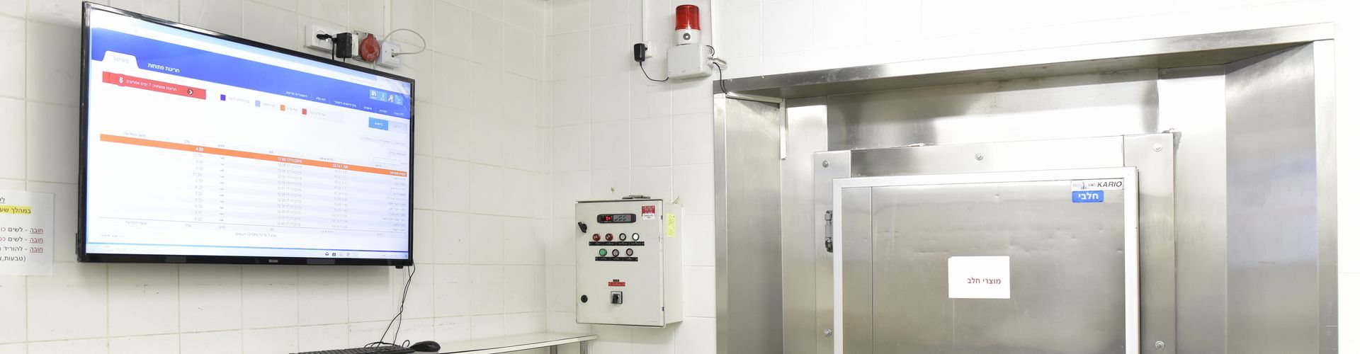 טלוויזיה תלויה על הקיר בחדר ליד מקרר.