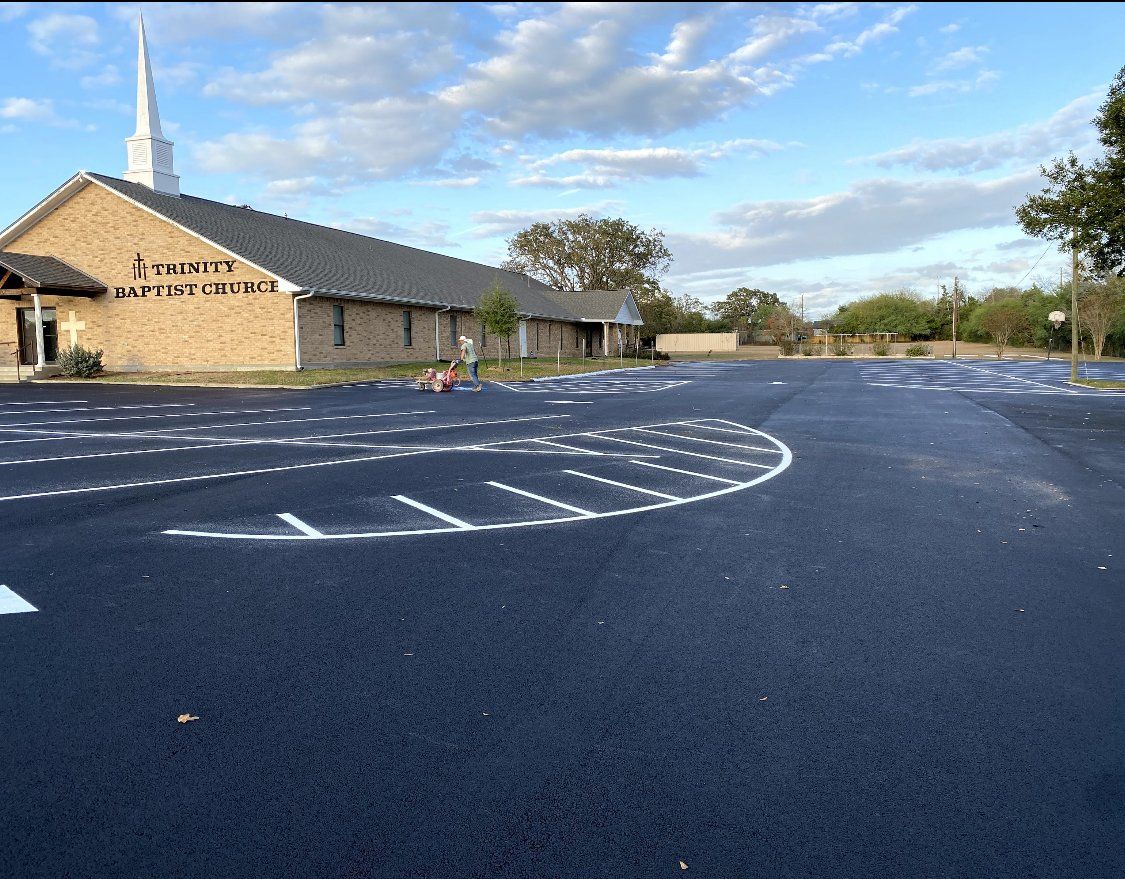 Empty blue parking lot beside a stone church under a partly cloudy sky