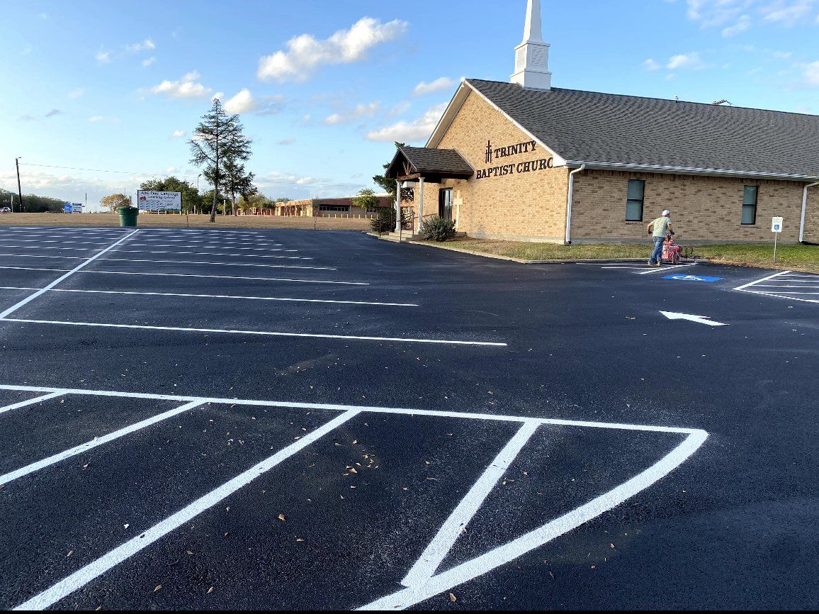 Empty church parking lot with painted white lines beside a brick church under a blue sky