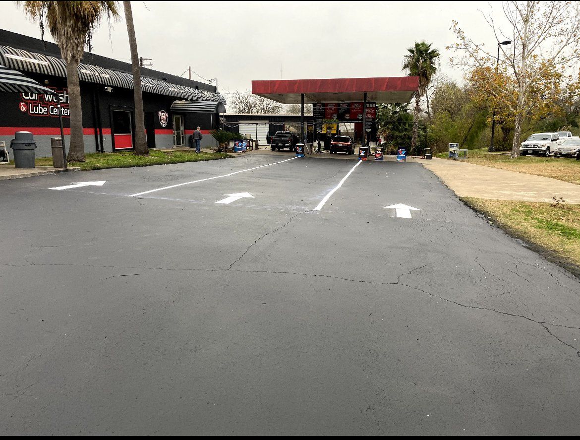 Empty parking lot with white directional arrows, a red awning, and trees in the background