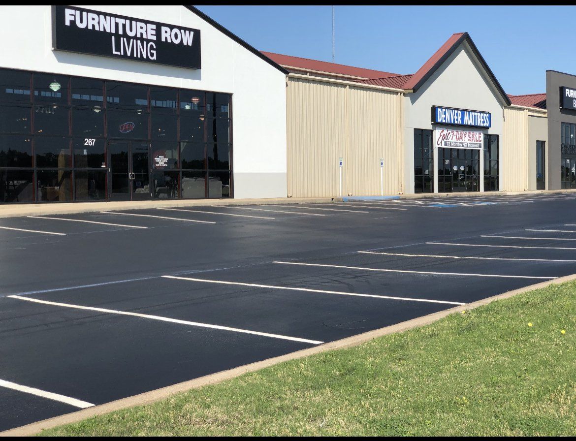 Furniture Row Living storefront in a strip mall with empty parking lot and grassy foreground